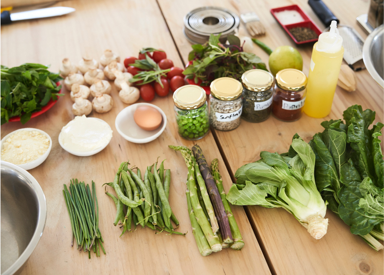 assorted green veggies and spices on wood table