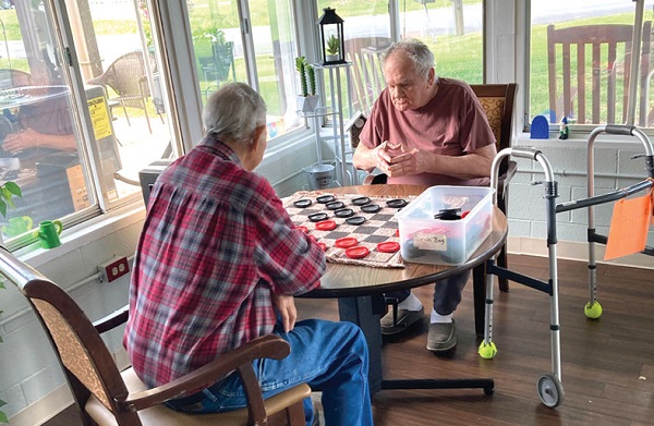 two older gentlemen playing checkers in the sunroom at Hardinsburg nursing and rehab