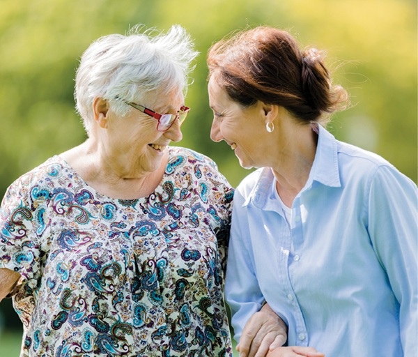 Older adult woman and adult woman smiling at each other